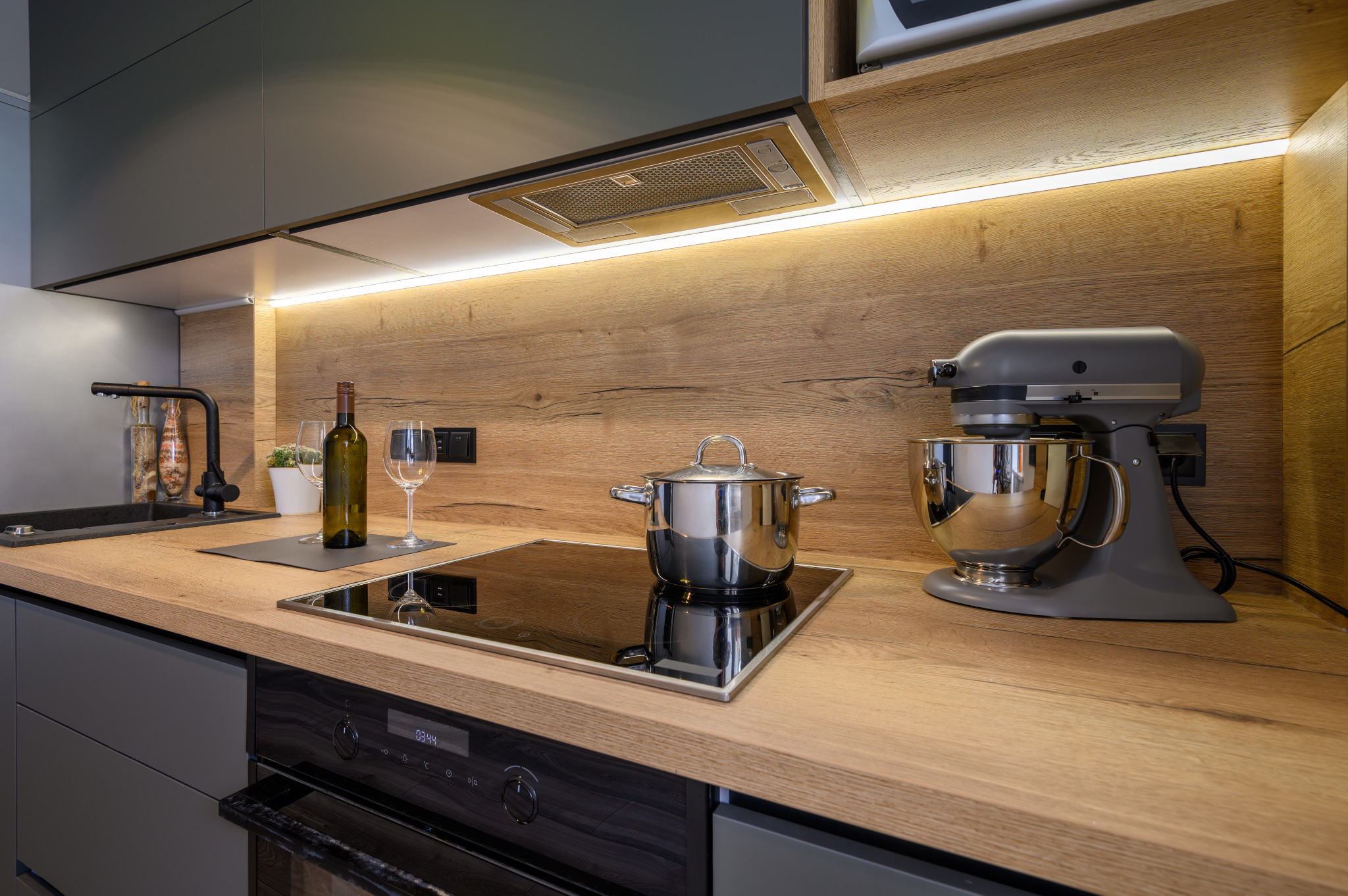 Modern kitchen after Worktop Refinishing in South West London, featuring a smooth oak worktop, oak wall cladding and matching engineered oak plank floor.
