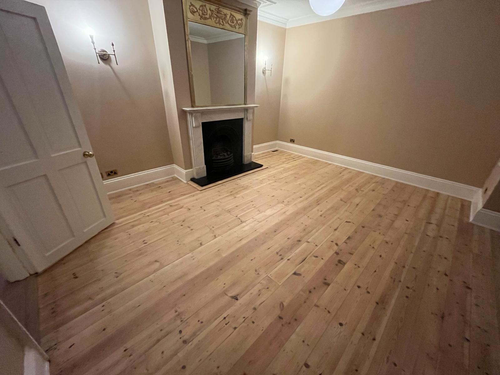 Wood Floor Sanding in South West London living room with freshly sanded pine softwood floorboards around period fireplace