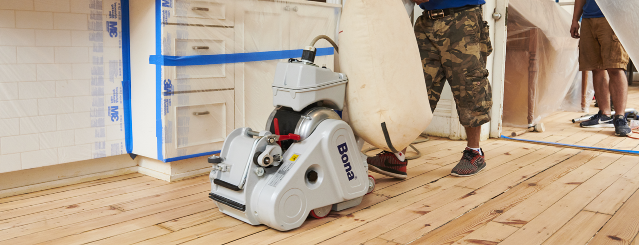 Wood Floor Sanding in south west london kitchen with Bona belt sander on solid pine floorboards, cabinets and walls fully protected